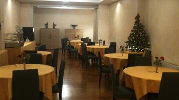 A dining area with round tables, chairs, and a Christmas tree.