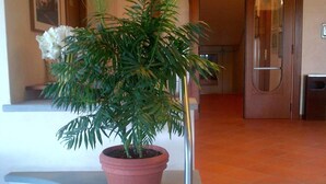 Ein Blumentopf auf einer weißen Ablage in der Nähe einer Treppe in einer Hotelhalle.