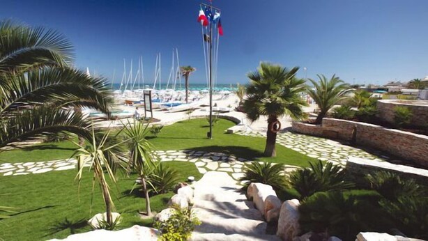 Un resort con zona de piscina, palmeras y vista despejada al océano.