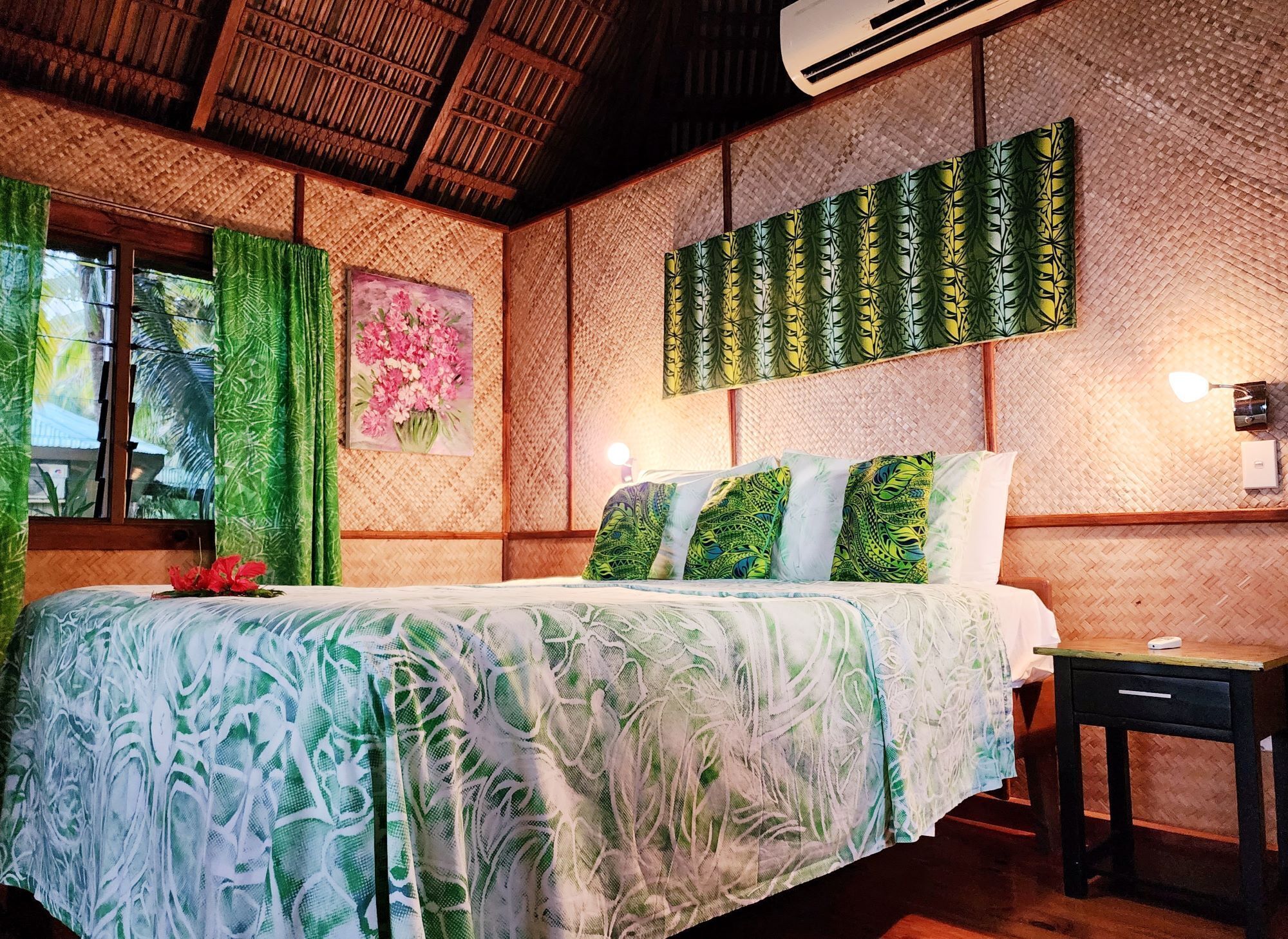 A room with a bed, a window with curtains, a wall with a woven pattern, and an air conditioning unit.