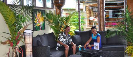A pool table in a room with a black sofa, a vase with flowers, and a large plant.
