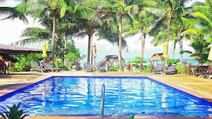 A pool area with lounge chairs and umbrellas, surrounded by palm trees and a view of the ocean. - Le Vasa Resort (Cape Fatuosofia)