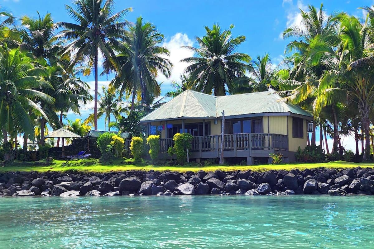 A beachfront property with a house, palm trees, and clear turquoise water.