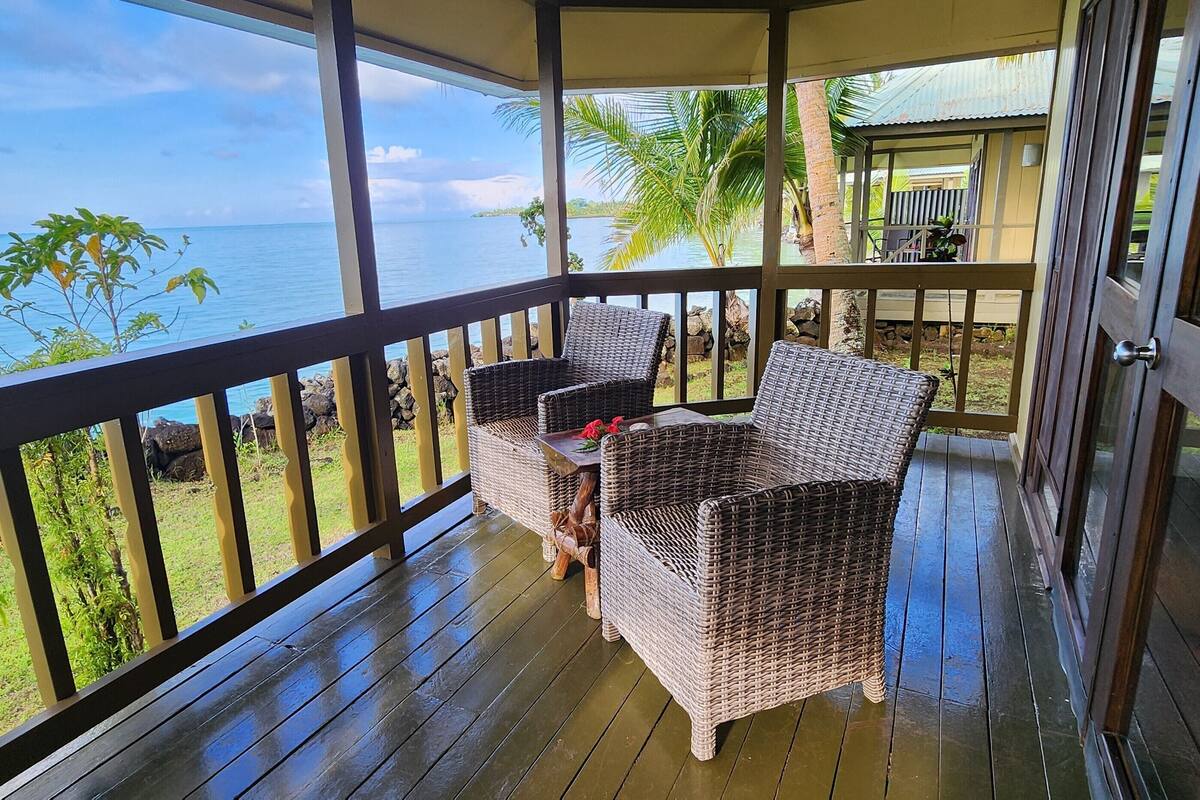 A covered outdoor area with wicker furniture and a view of the sea.