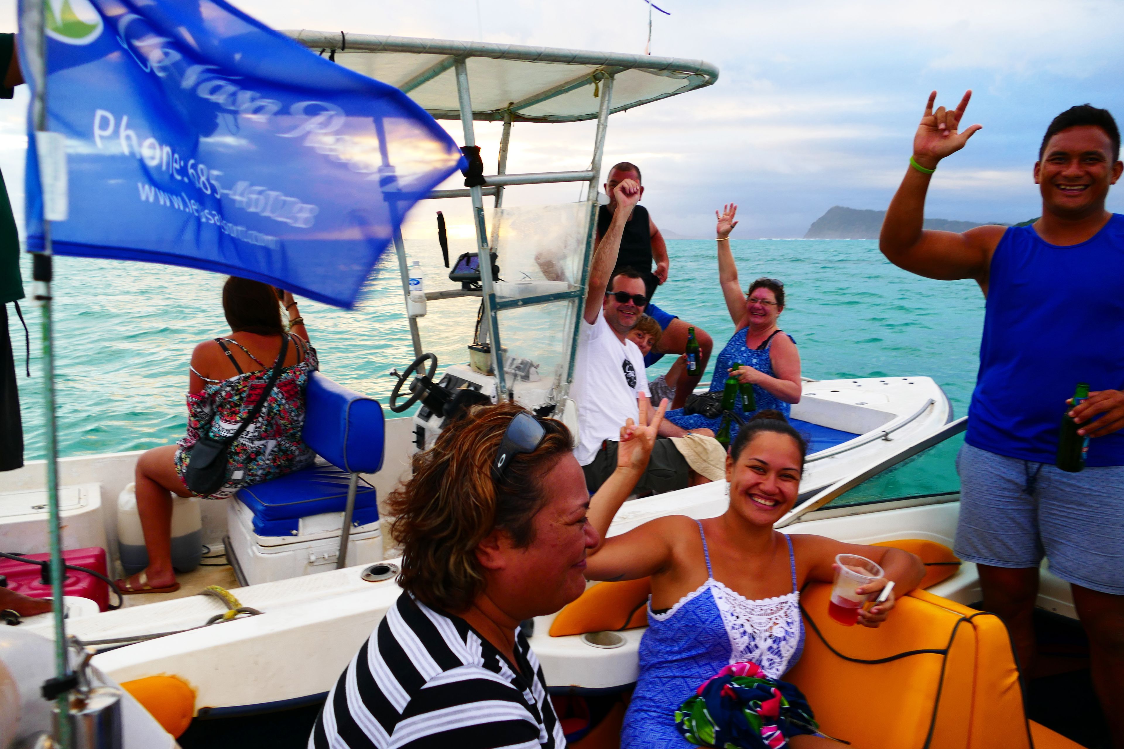Un barco con pasajeros, una bandera azul y una masa de agua al fondo.