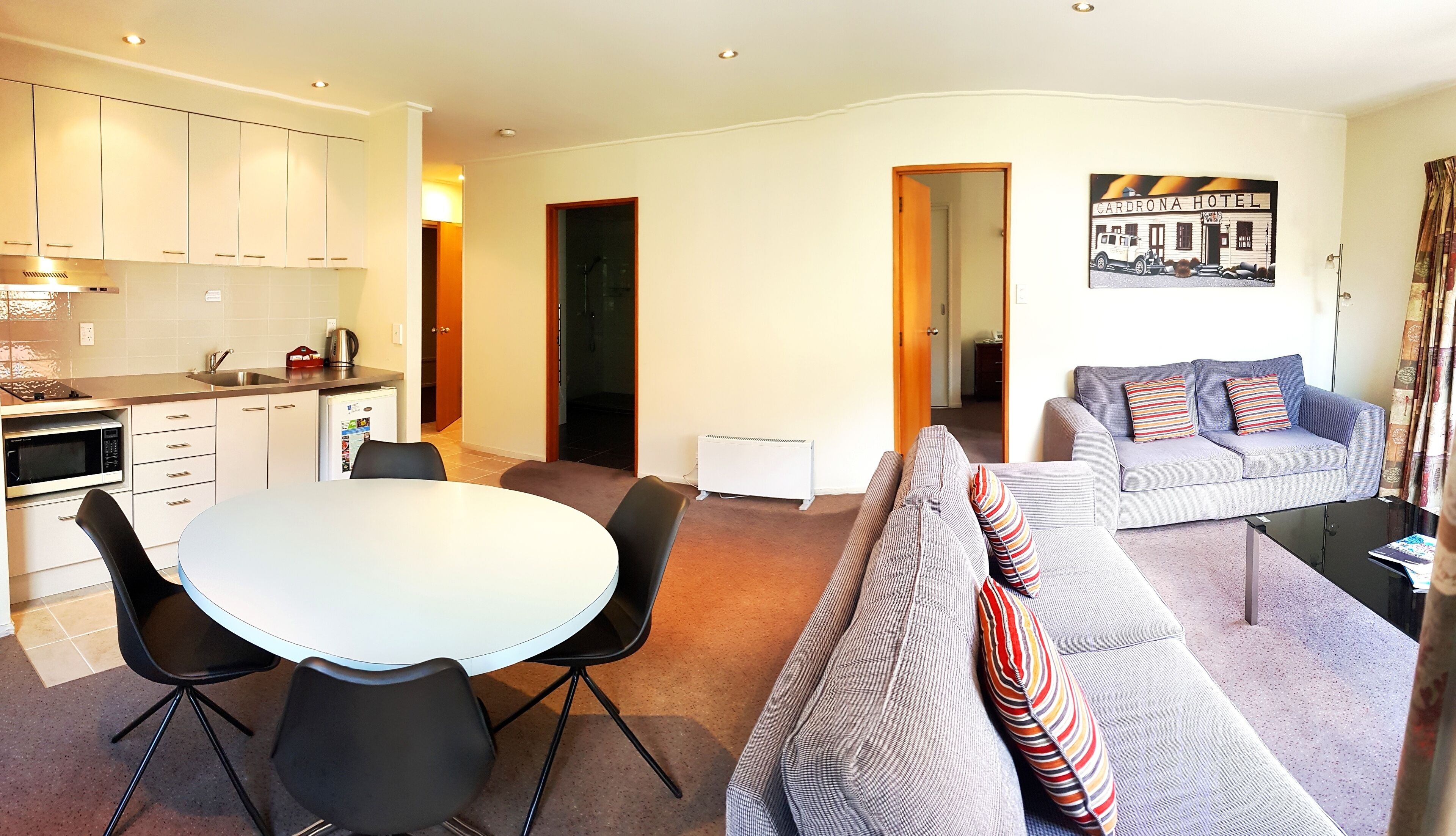 Een compacte leefruimte met een kitchenette, een eethoek en een zithoek met een bank en een tafel.