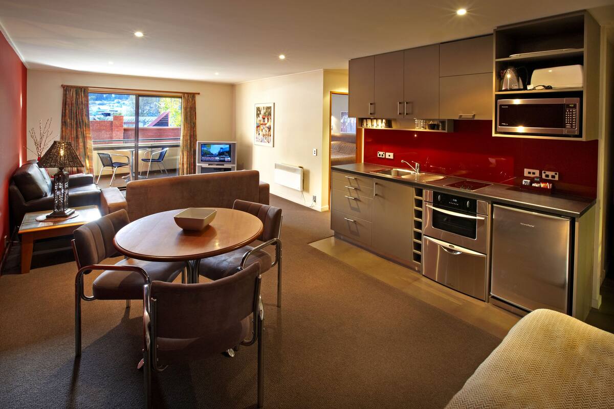 A modern apartment with a dining area, kitchen, and a balcony with a view.