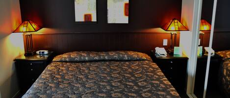 A hotel room with a large bed, two bedside tables, two wall-mounted lamps, and a sliding glass door.