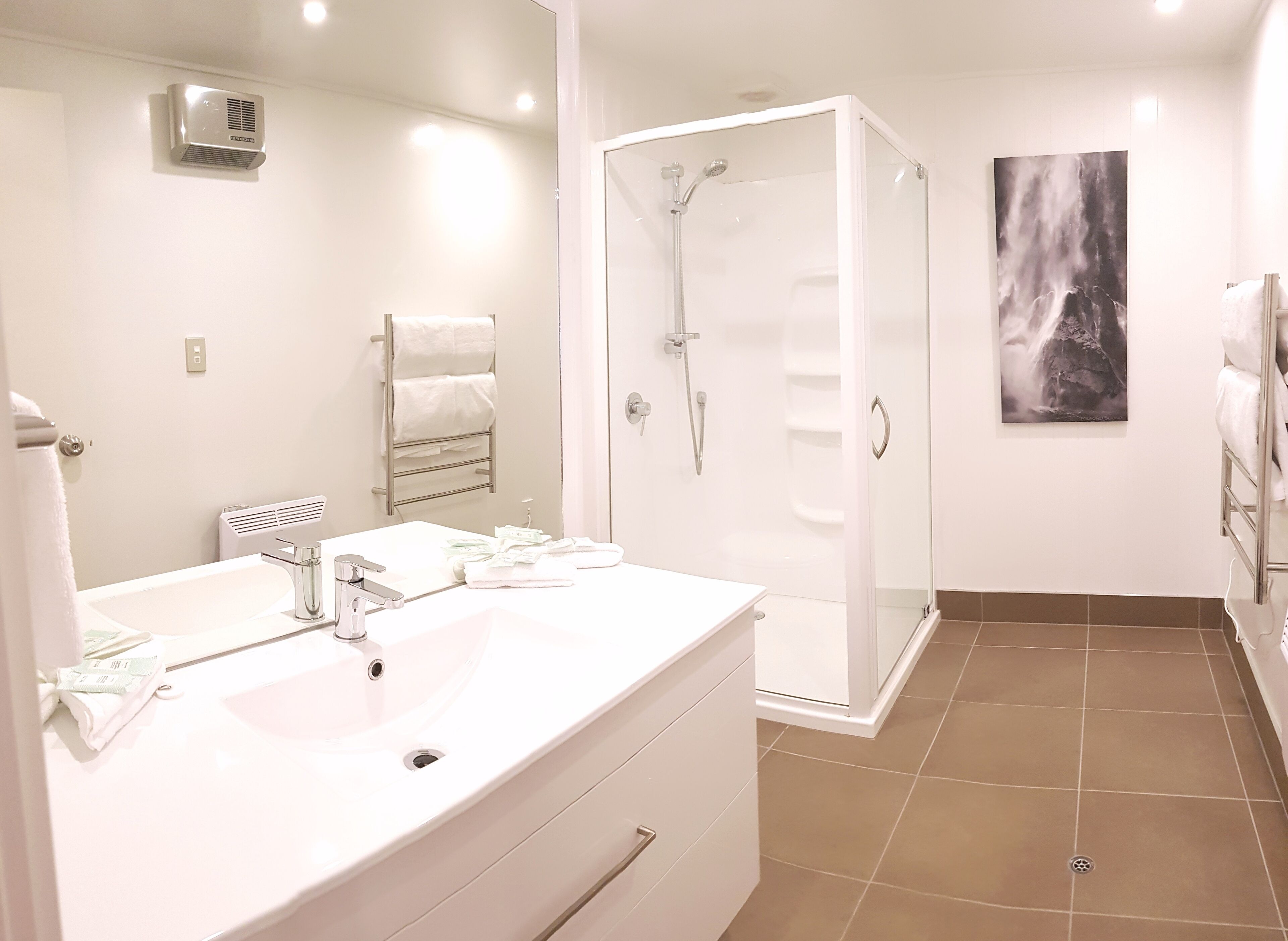 A modern bathroom with a large sink, a glass shower enclosure, and a towel rack.