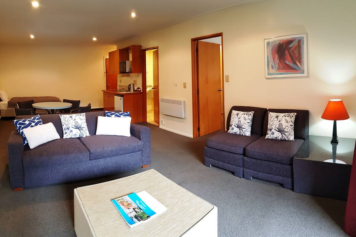 A living room with two sofas, a coffee table, and a dining area with a table and chairs.