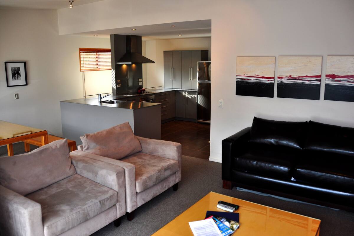 A modern living room with a sofa, a coffee table, and a black leather couch.
