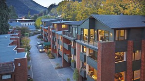 Un edificio moderno de varios pisos con balcones, ventanas amplias y un camino de entrada pavimentado.