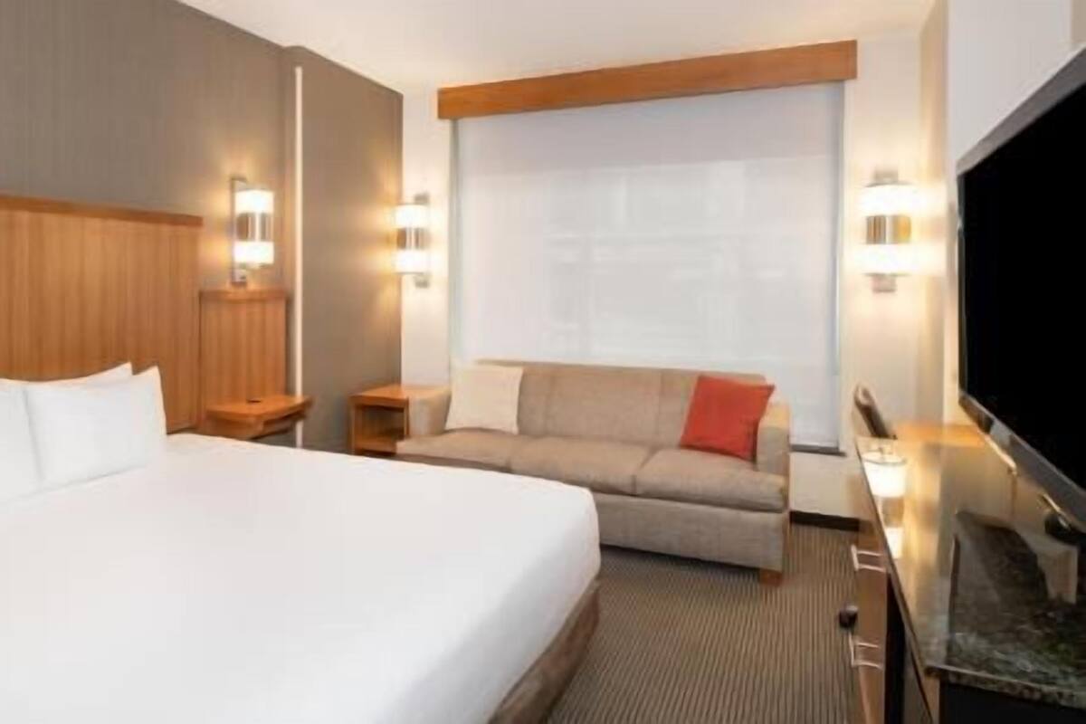 Ein Hotelzimmer mit Bett, Sofa, Fernseher und Fenster.