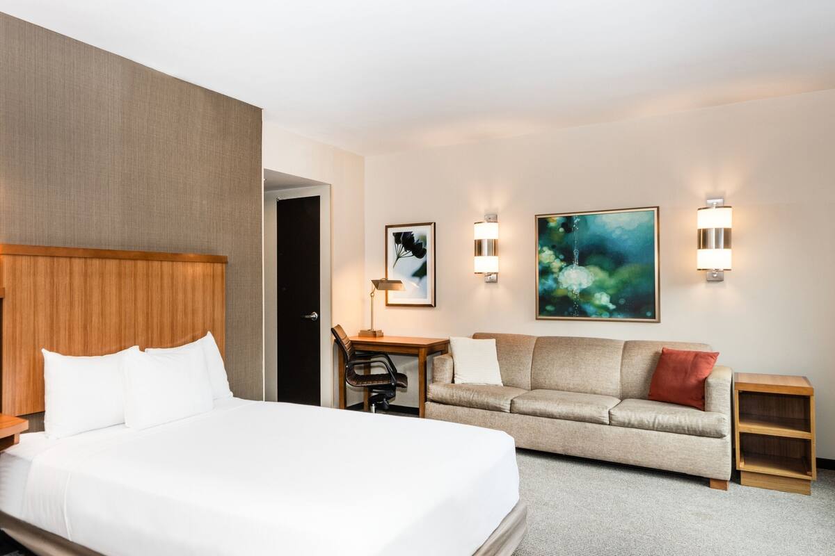 Ein Hotelzimmer mit zwei Betten, einer Couch, einem Schreibtisch und einem Sessel.