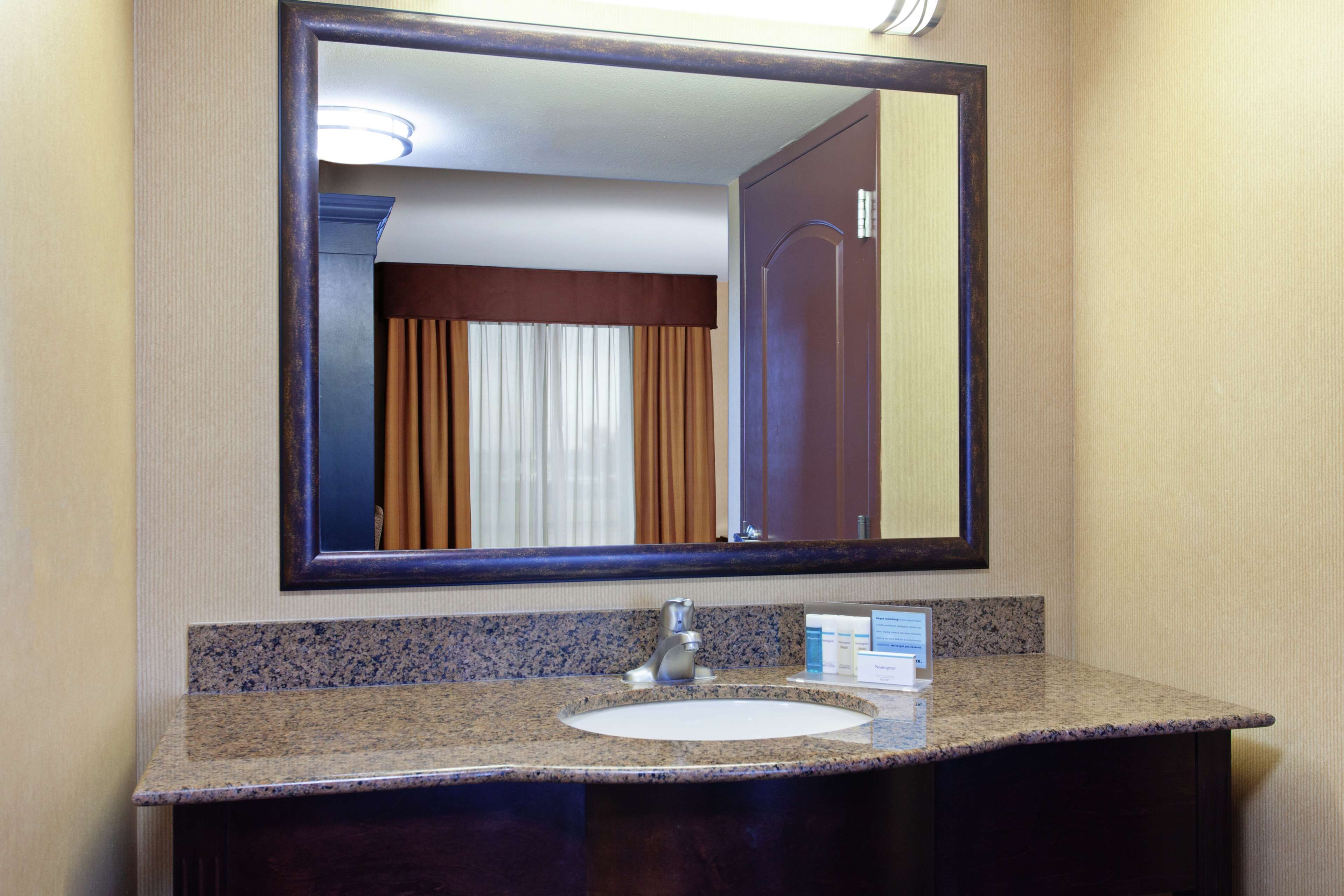 A bathroom with a granite countertop, a sink, and a mirror.