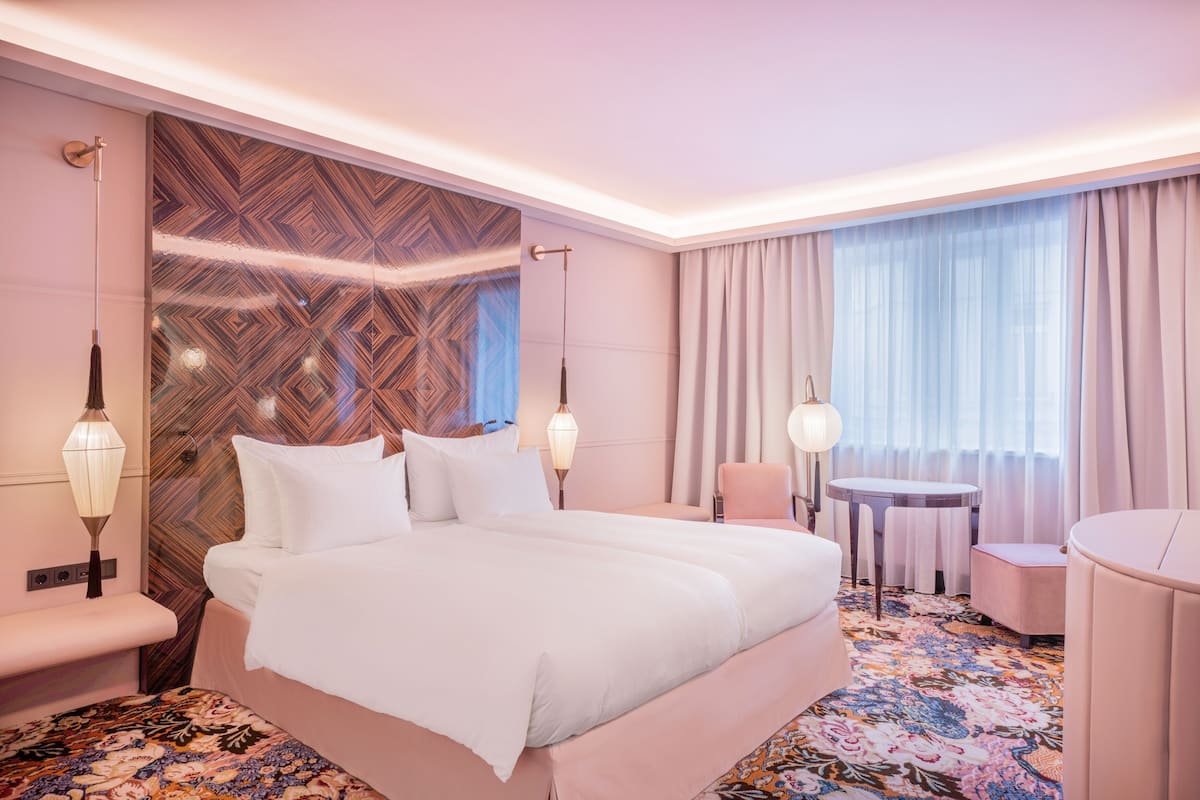 A hotel room with a large bed, a small round table, a chair, and a sofa.
