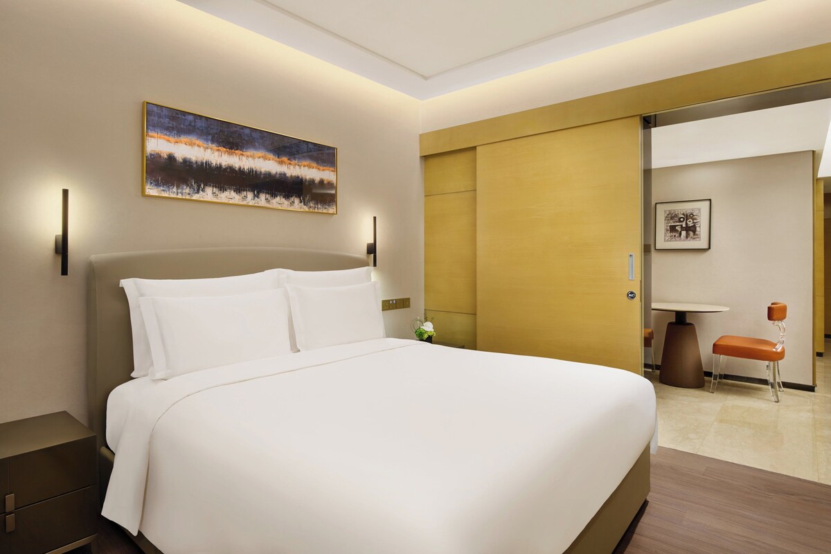 Une chambre d’hôtel avec un grand lit, un tableau au mur, un bureau et une chaise.