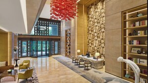 A spacious lobby with a reception desk, seating area, and a large bookshelf.