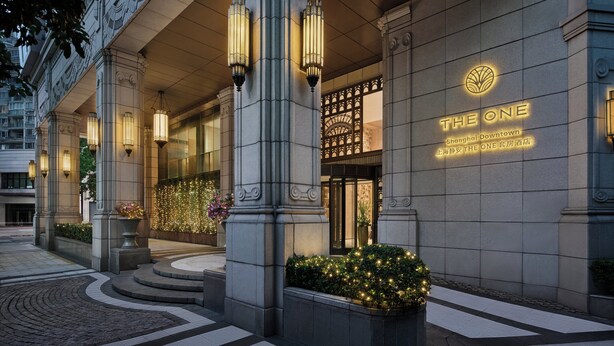 A hotel entrance with a prominent sign, large columns, and decorative lighting.