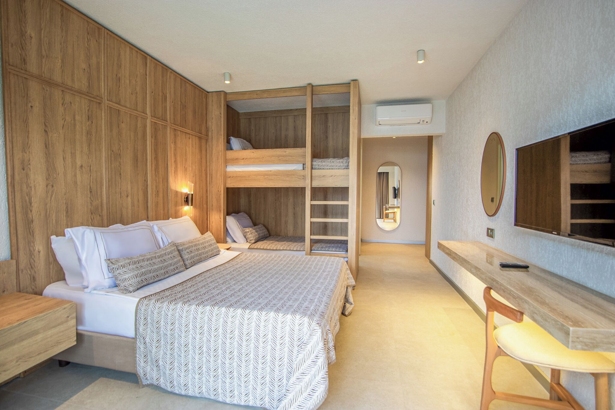 A bedroom with a bunk bed, a desk, a chair, and a large mirror.