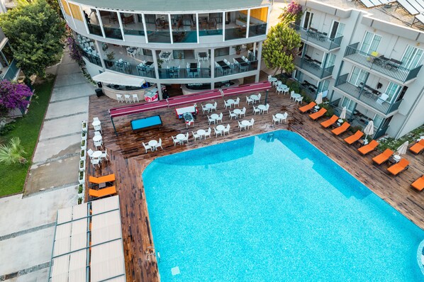 A modern hotel with a large pool, outdoor seating, and a multi-level structure with balconies.