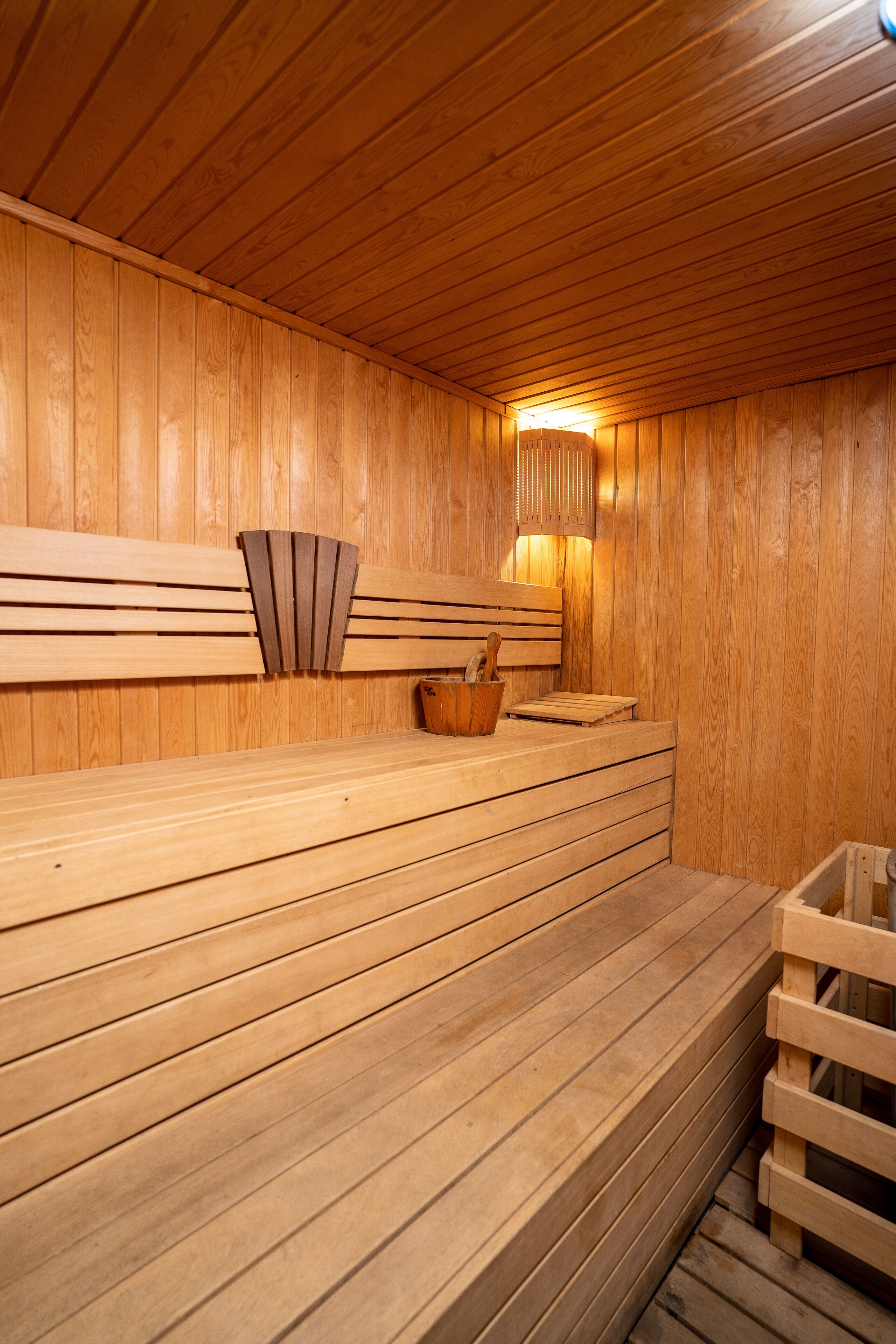 Una sauna de madera con bancos y un banco con perchero para toallas.