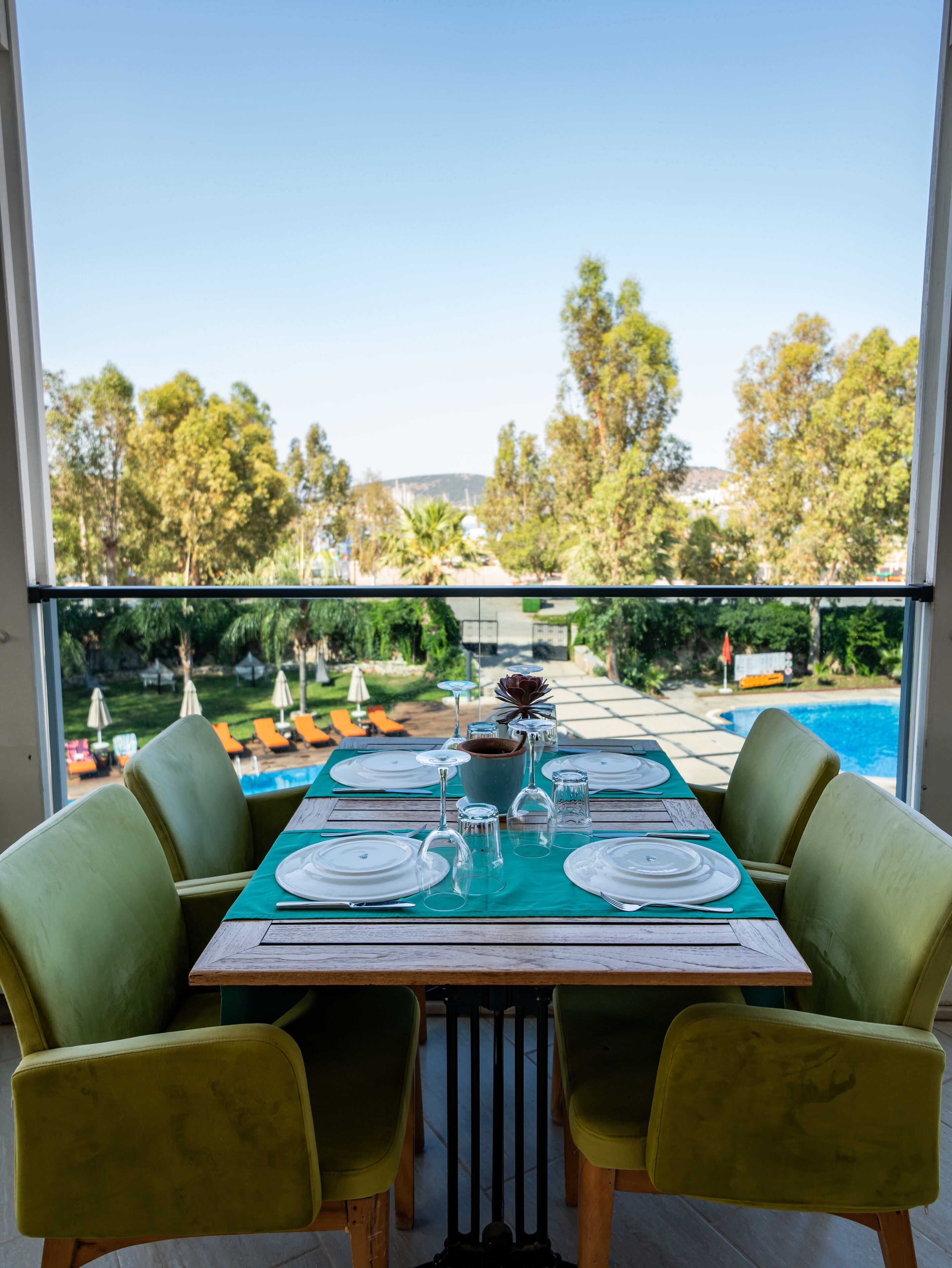 A dining table set for four with a view of a pool and greenery.