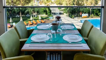 A dining table set for four with a view of a pool and greenery.