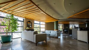 A spacious living area with a high ceiling, large windows, and a potted plant. - Bodrum Beach Resort (Bodrum)