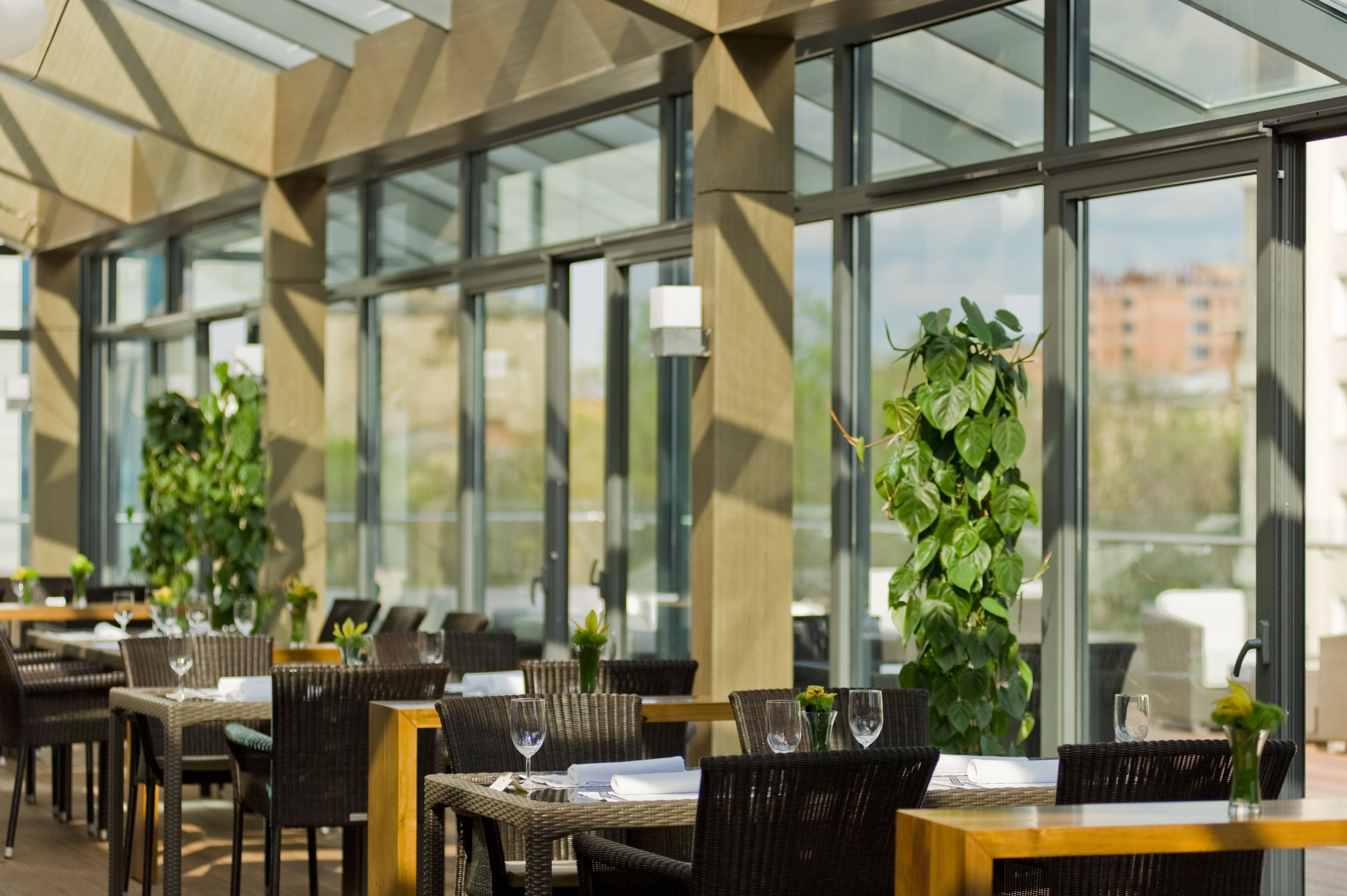 Un restaurante con terraza, amplias ventanas y plantas en macetas.