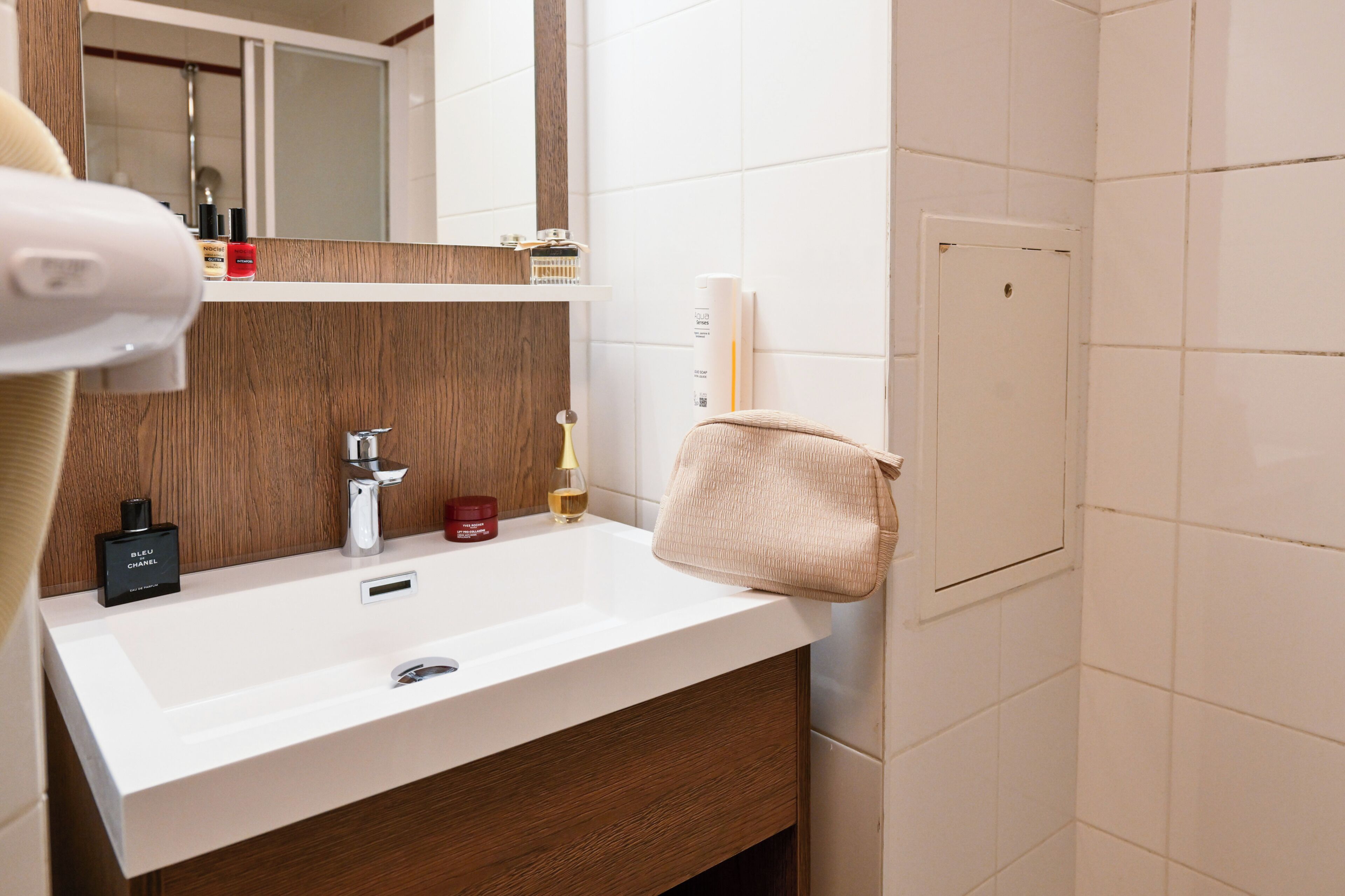 Un baño con un lavabo blanco, tocador de madera y una toalla colgada en la pared.