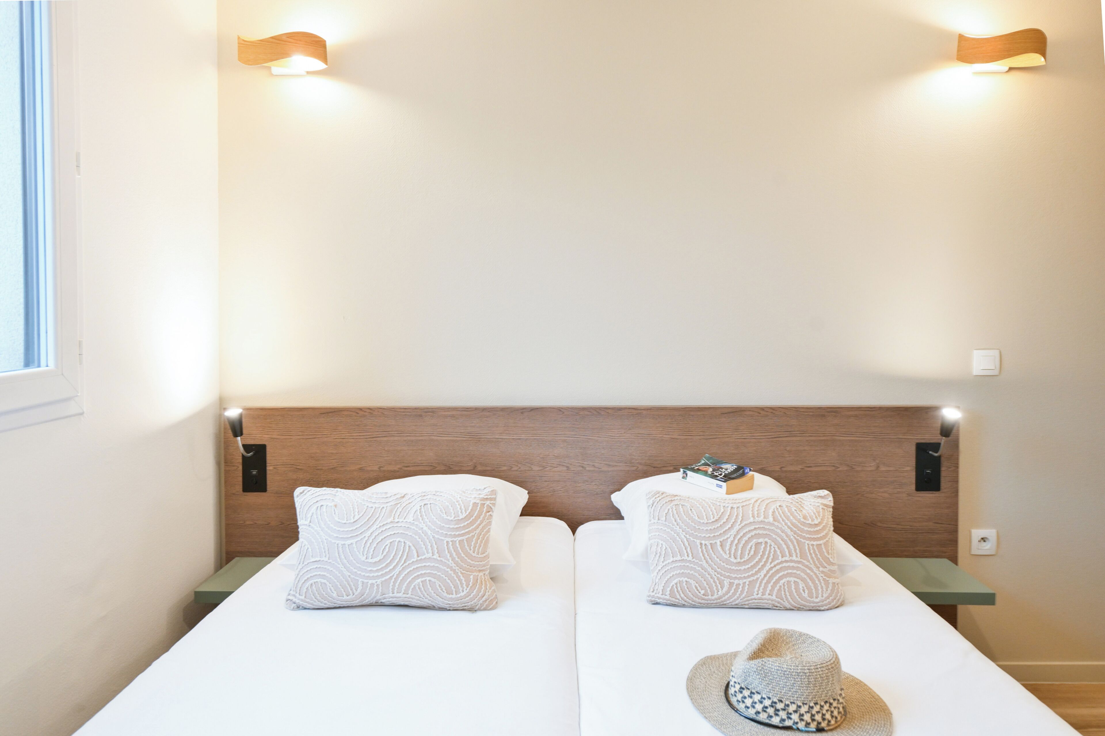 Un lit double avec des coussins à motifs, une tête de lit en bois et des tables de chevet.