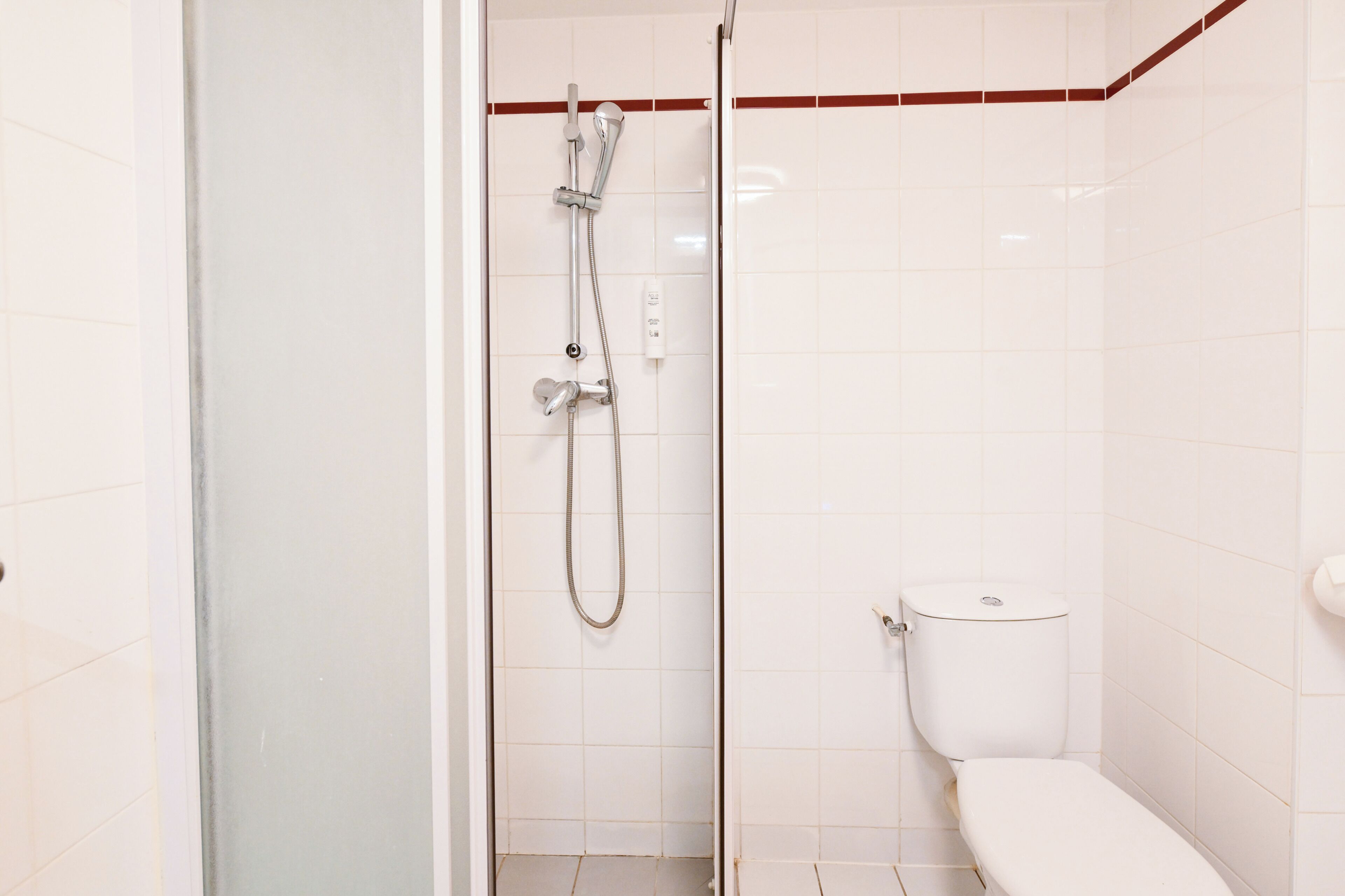 A small, clean bathroom with a shower, toilet, and a glass door.