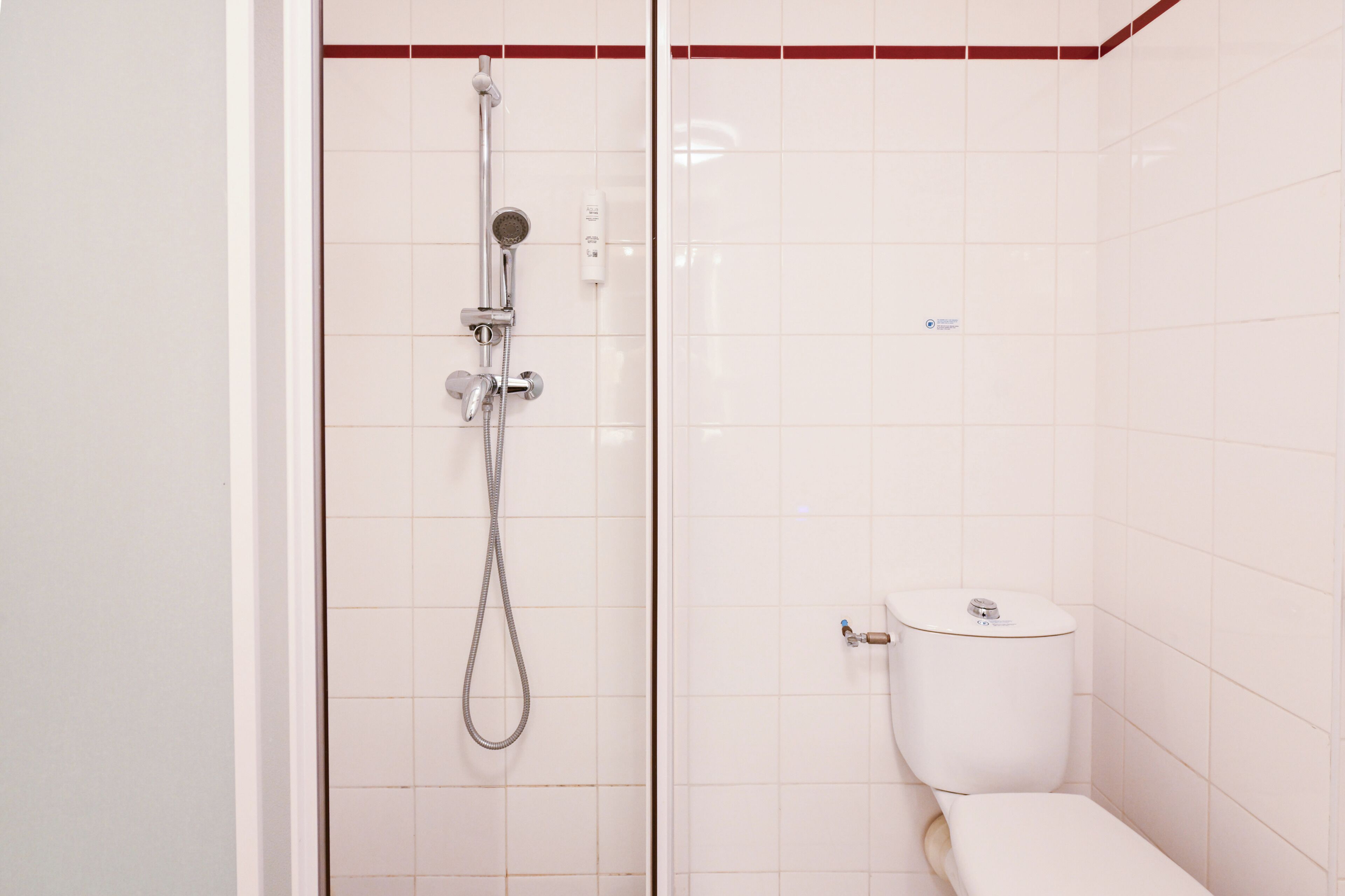 A bathroom with a shower, toilet, and a wall-mounted phone.