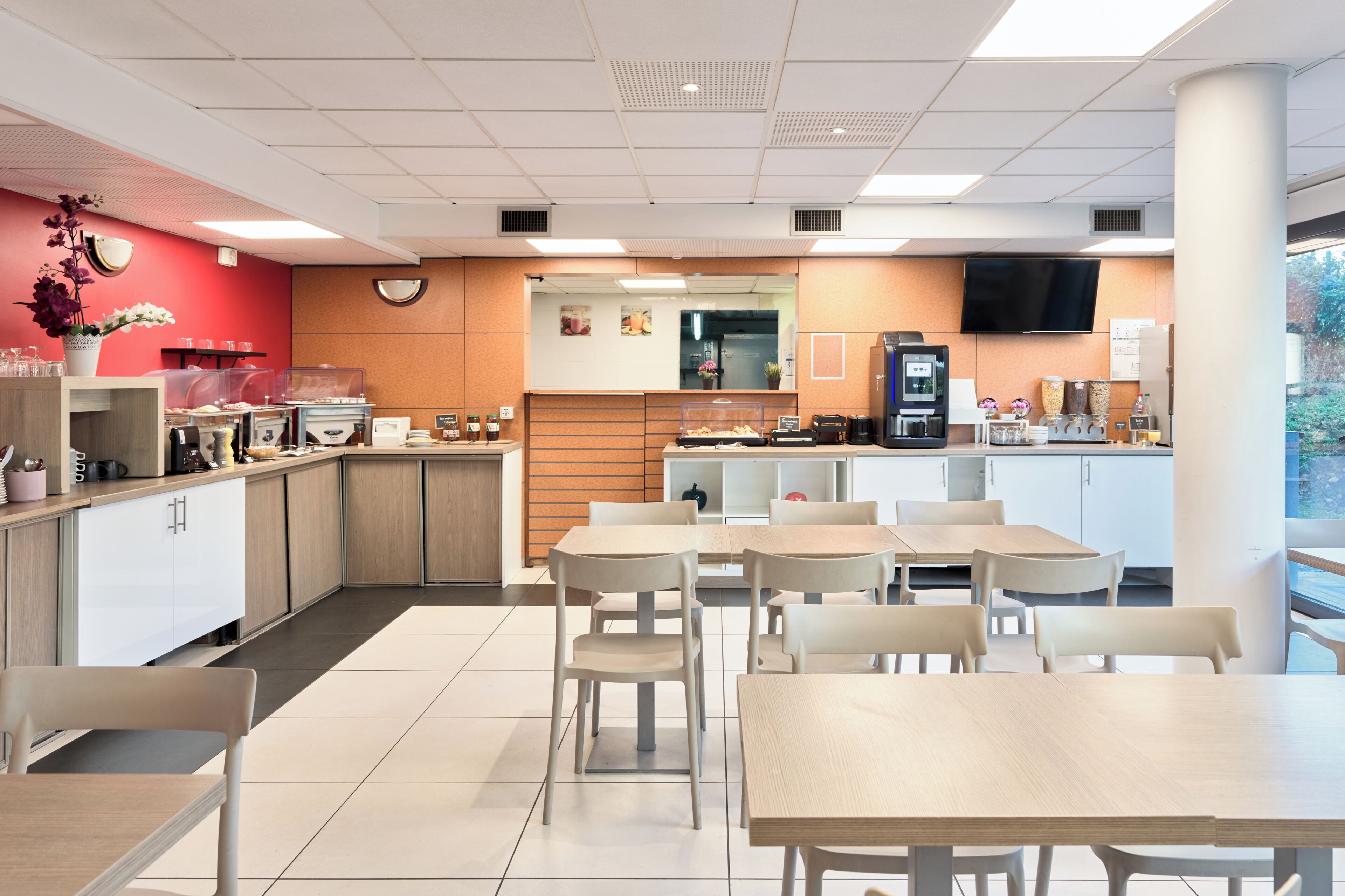 Een modern café met een balie, een zithoek en een televisie aan de muur.