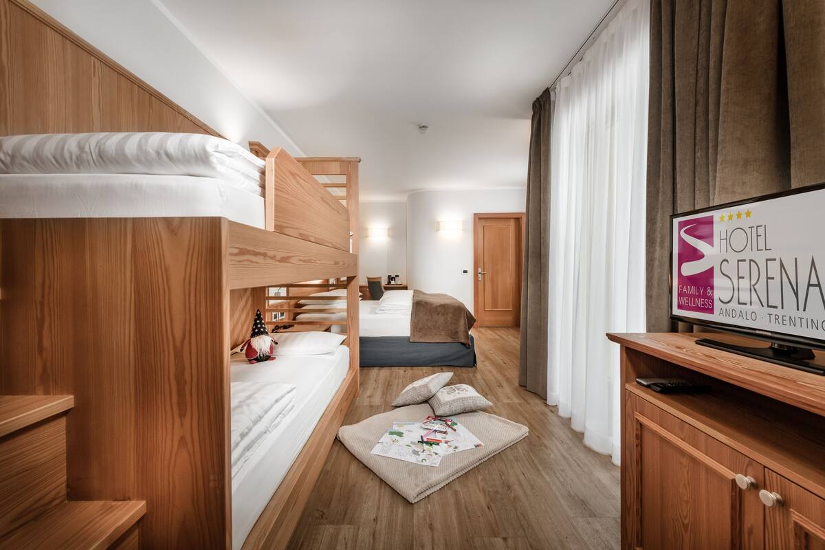 Une chambre d’hôtel équipée de lits superposés, d’une télévision et d’une enseigne indiquant le nom et l’emplacement de l’hôtel.