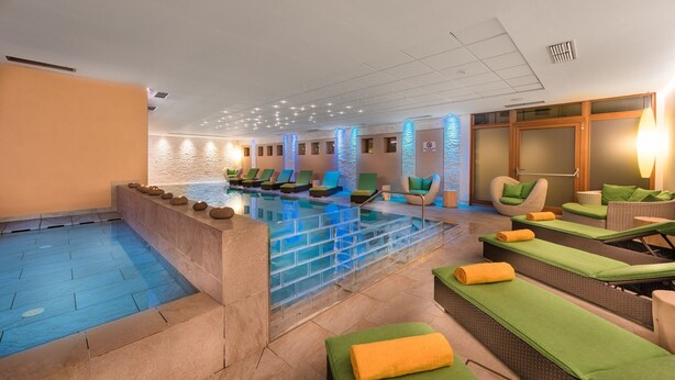 Ein Schwimmbad mit Liegestühlen und einem Wellnessbereich.