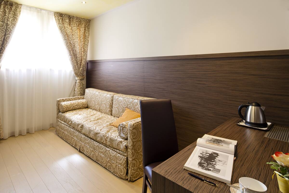 Une chambre moderne avec un canapé à motifs, un bureau en bois, une bouilloire et un livre.