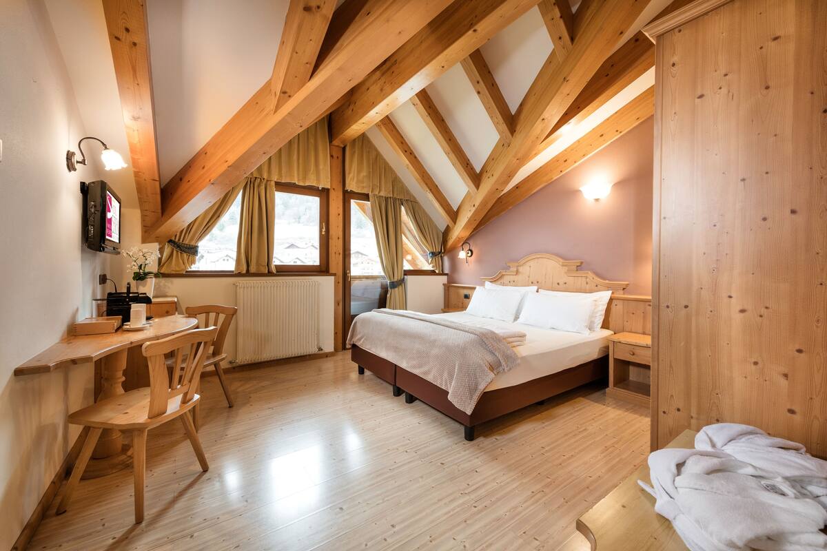 Une chambre avec un plafond en bois, un lit, un bureau et une chaise.