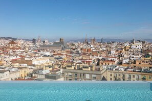 A cityscape with a pool in the foreground, buildings, and a distant cathedral. - Hotel Andante Drassanes (Barcelona)
