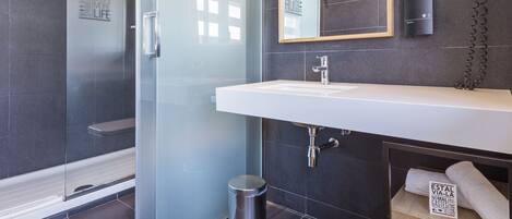 Un baño moderno con cabina de ducha de vidrio, un lavabo blanco y un perchero para toallas.