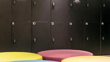 A row of numbered lockers with a keypad lock, and colorful stools in the foreground.