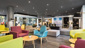 A modern lobby with colorful seating, a reception desk, and a cityscape poster. - Hotel Andante Drassanes (Barcelona)