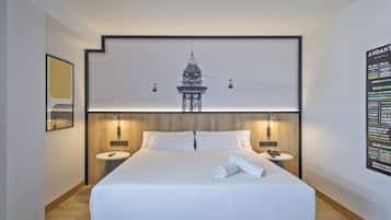A modern hotel room with a large bed, two bedside tables, a wall-mounted TV, and a poster on the wall.