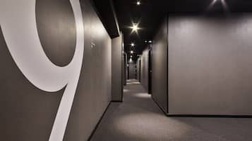 Un pasillo moderno con un grande '9' blanco en la pared izquierda, que conduce a varias puertas.