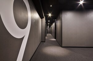 Um corredor moderno com um grande '9' branco na parede esquerda, que leva a várias portas.
