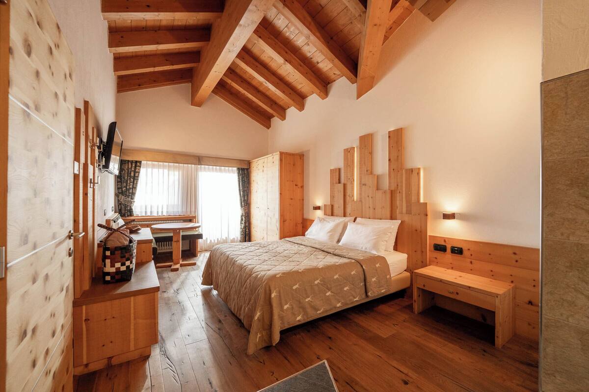 A wooden bedroom with a bed, bedside tables, and a window.