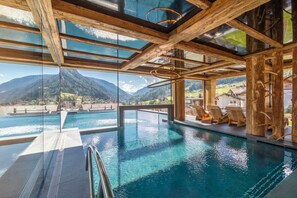 Une piscine intérieure offrant une vue dégagée sur les montagnes et un village.