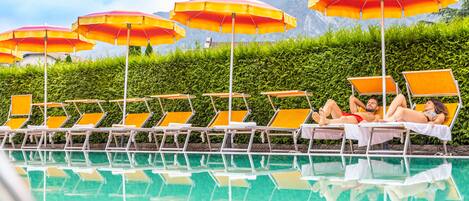 Een buitenzwembad, parasols bij het zwembad en ligstoelen