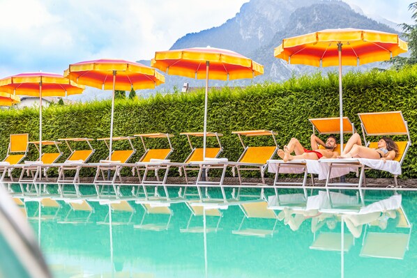 Een buitenzwembad, parasols bij het zwembad en ligstoelen